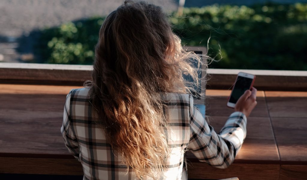 woman checking email on mobile at the beach