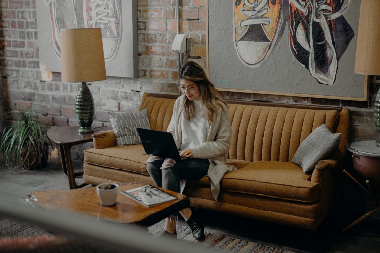 A young woman sits in a well-decorated living room, demonstrating remote working in 2023