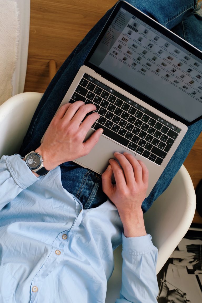 A view from above of a laptop on a man's lap. On the screen is a library of folders and documents, one of the essential intranet features