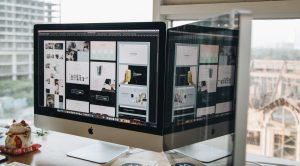 A large Mac screen is lit up with design choices, against the backdrop of a bright window. We explain essential intranet features for 2023