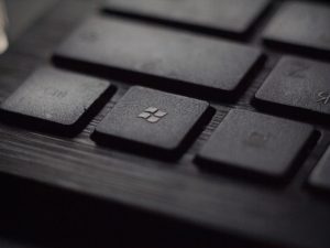 A close up of a button on a black keyboard that has the Microsoft logo. It shows how Microsoft Sharepoint and other apps can be a shortcut for productivity.