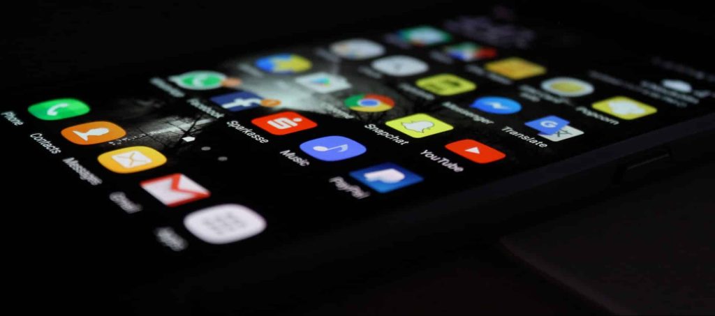 A smartphone screen laying horizontal on a dark surface, unlocked to show apps covering the screen.