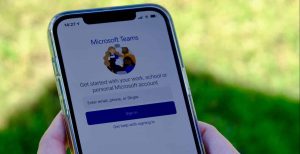 A closeup of two hands holding a smartphone open to Microsoft Teams