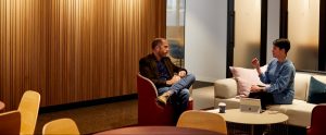 A man and a woman sit around a low coffee table, discussing file naming conventions