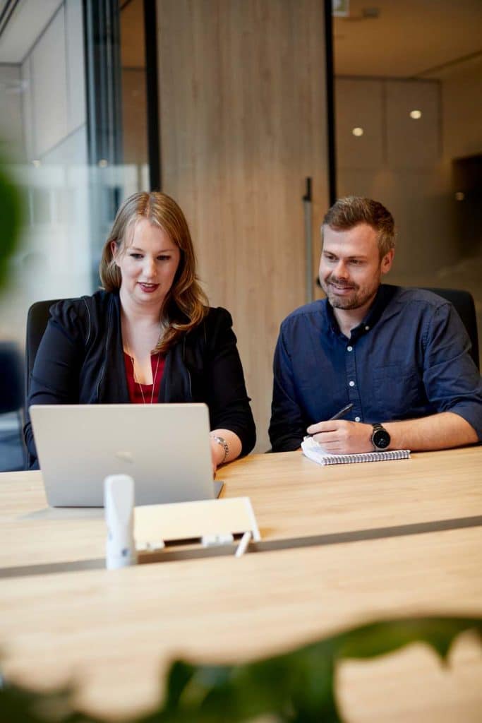two colleagues sit side by side automating workflows with power automate