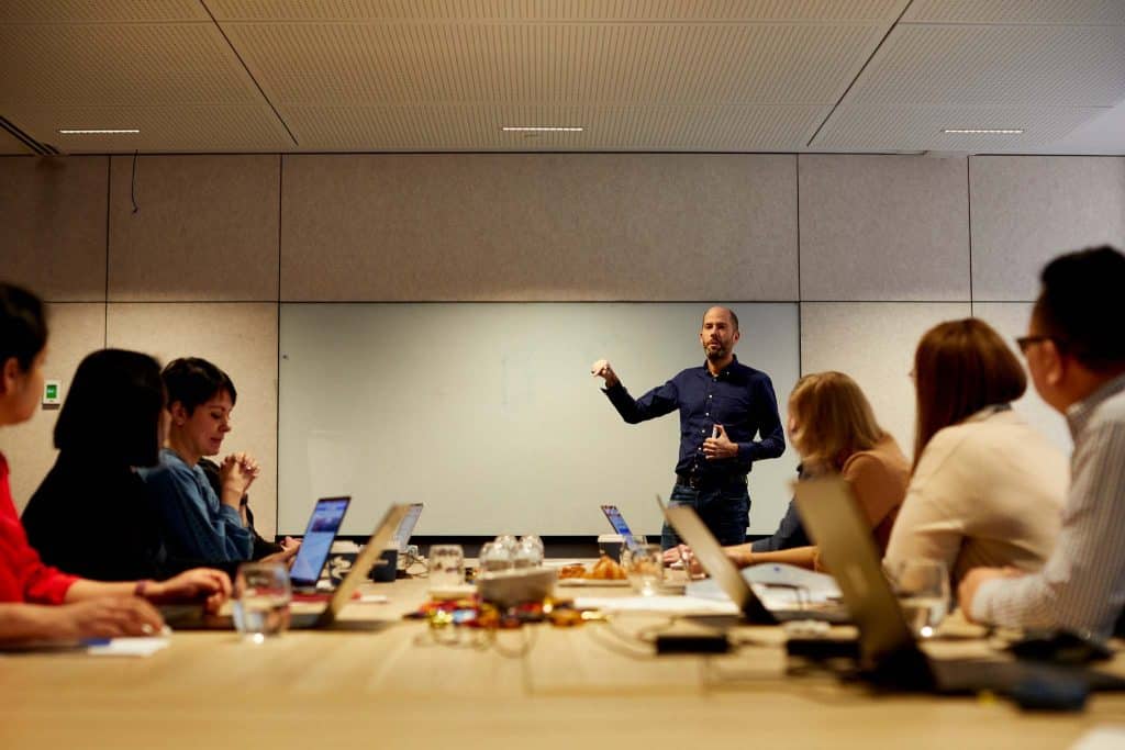 man standing and presenting to a group of company managers sitting in a conference room about planning document management
