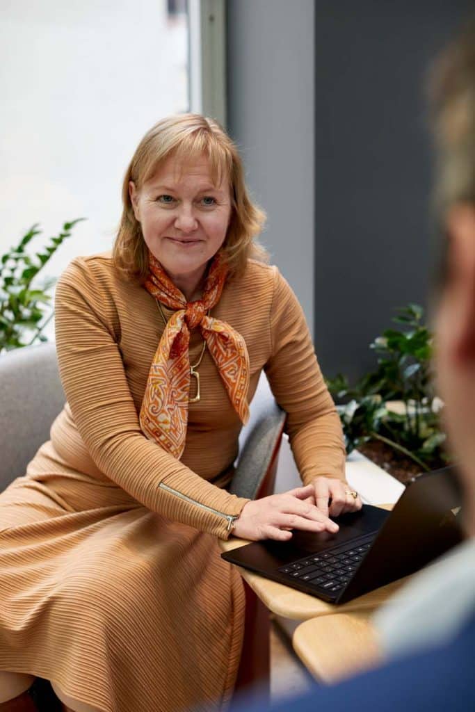 A woman sits at a table, a laptop open in front of her as she chats to a client about understanding sharepoint permissions