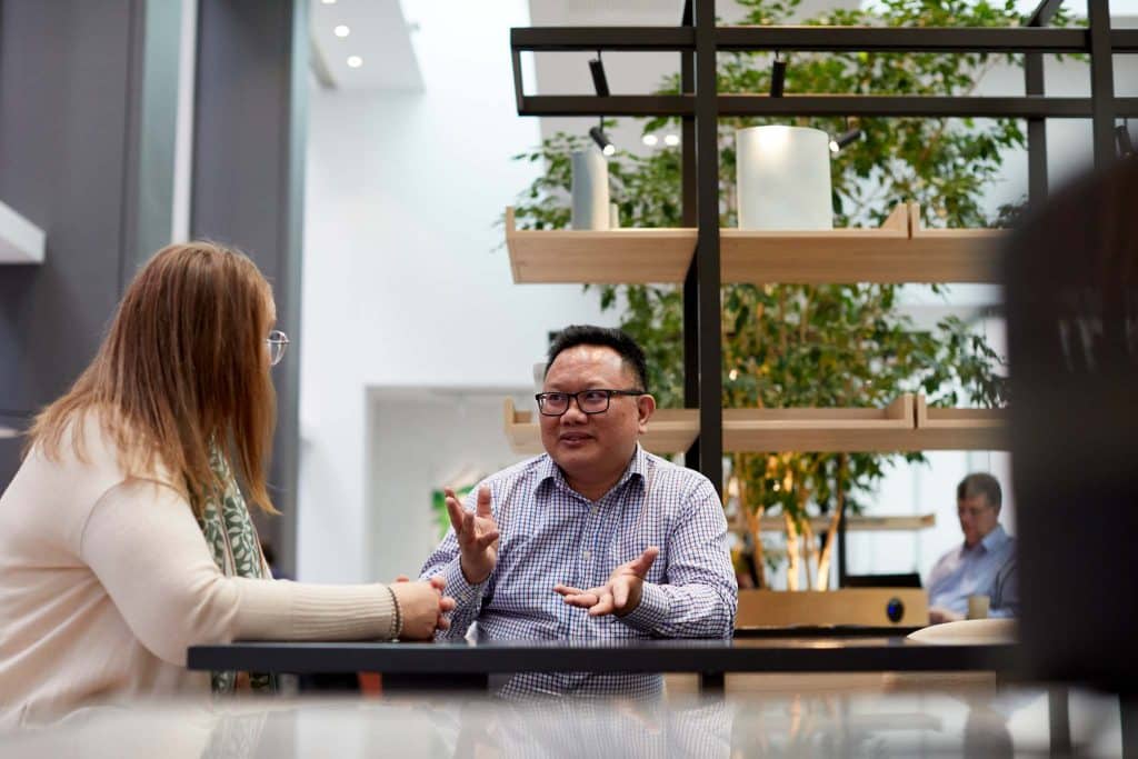 two colleagues sit at a table discussing the success of using the intranet for employee onboarding