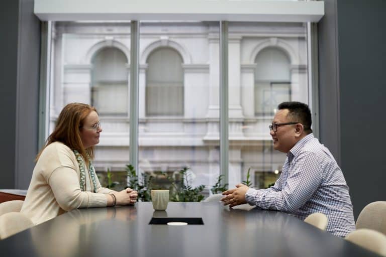 Man and a woman sitting at a table discussing SharePoint employee engagement