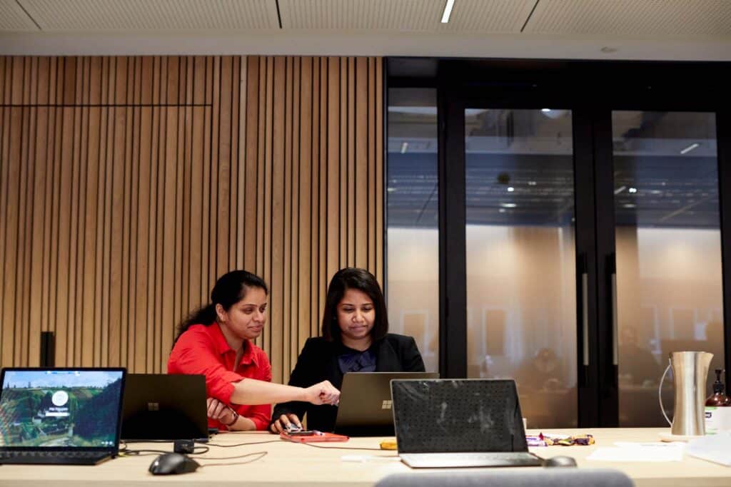 2 employees at a table with laptops in front of them