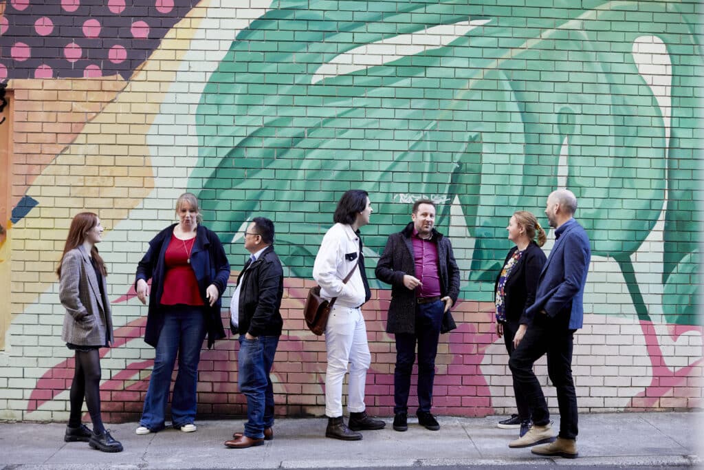 People standing in front of a painted brick wall