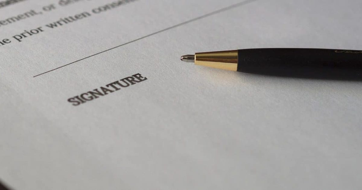 A close up of the last page of a contract and a pen. The world 'SIGNATURE' is at the bottom.