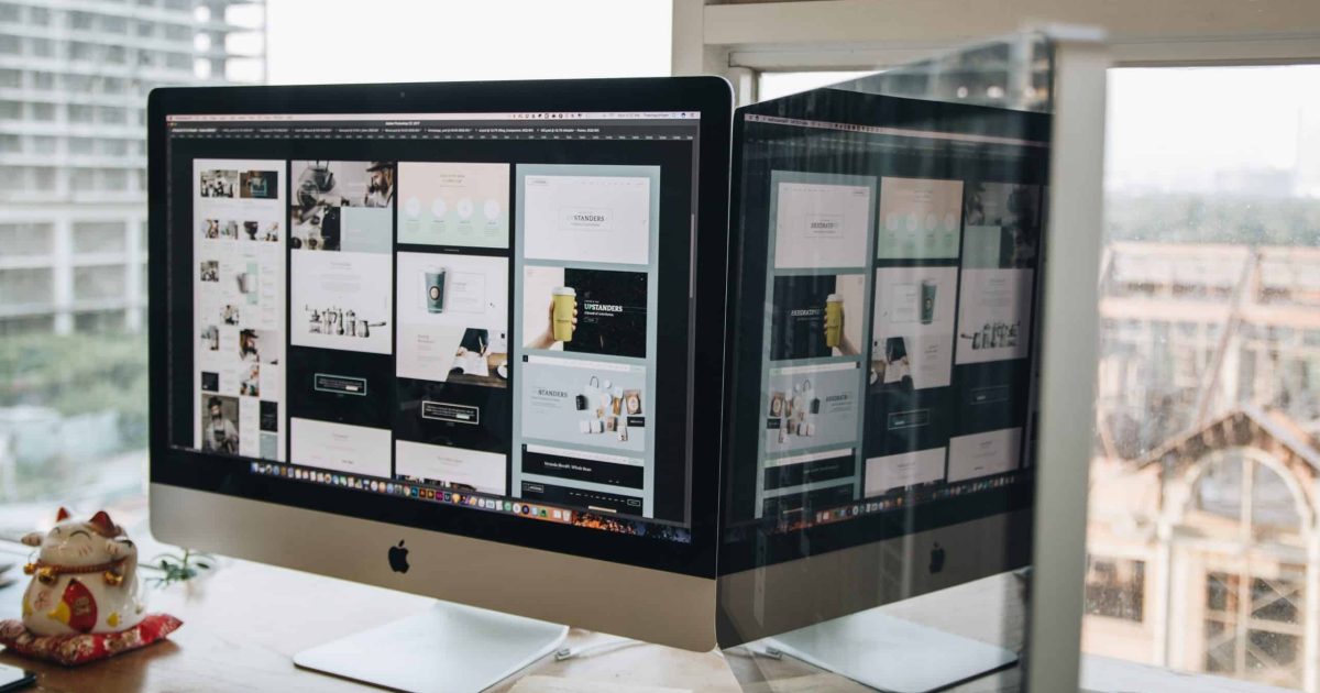 A large Mac screen is lit up with design choices, against the backdrop of a bright window. We explain essential intranet features for 2023