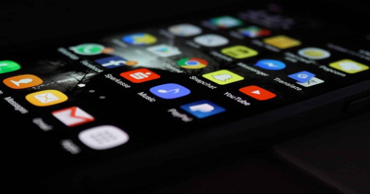 A smartphone screen laying horizontal on a dark surface, unlocked to show apps covering the screen.
