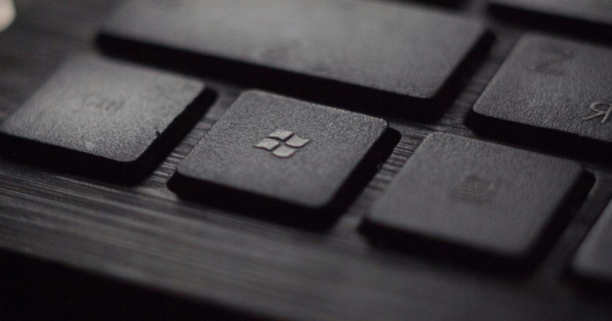 A close up of a button on a black keyboard that has the Microsoft logo. It shows how Microsoft Sharepoint and other apps can be a shortcut for productivity.